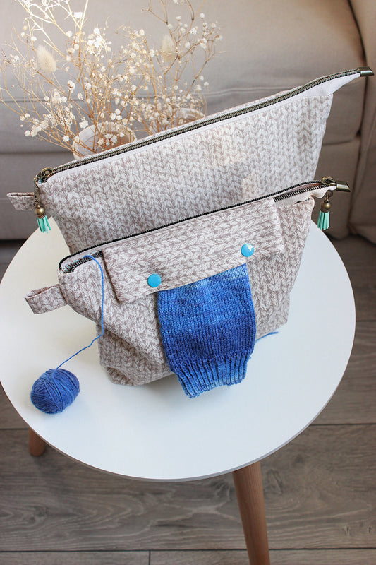 Beige knitting project bag with blue accents, holding yarn on a table, perfect for organizing knitting or crochet supplies.